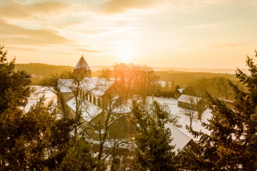 Ein Foto des Sonnenaufgangs über dem Kloster Schiffenberg bei Gießen. Die Umgebung und auch das Kloster sind mit Schnee gedeckt. Durch den Sonnenaufgang ist das Bild aber in warmes Licht getaucht.